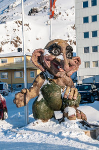 Statue on snow in city against sky