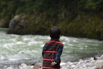 Rear view of boy looking at waterfall