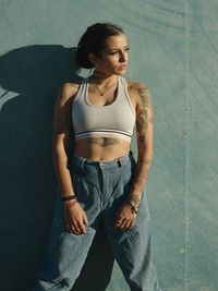 Young woman looking away while sitting on wall