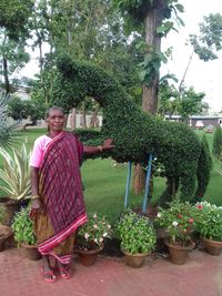 Portrait of smiling woman standing by potted plants