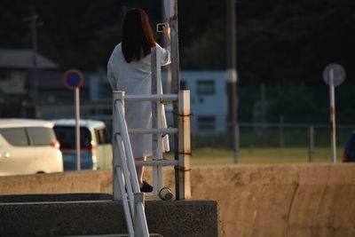 Rear view of woman photographing while standing on footpath