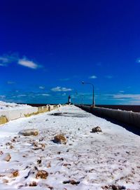 Snow covered pier against blue sky