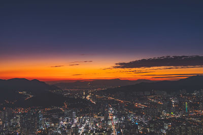 Aerial view of illuminated cityscape against sky during sunset