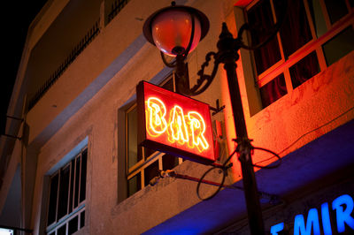 Low angle view of illuminated sign on building at night