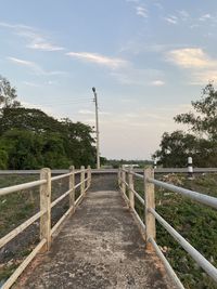 Footpath by railing against sky