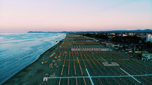 High angle view of city by sea against sky during sunset