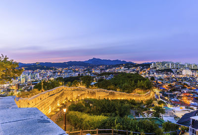 High angle view of illuminated city against sky at dusk