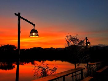 Silhouette trees by lake against sky during sunset