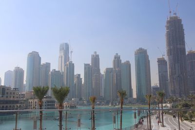 Modern buildings by swimming pool in city against sky