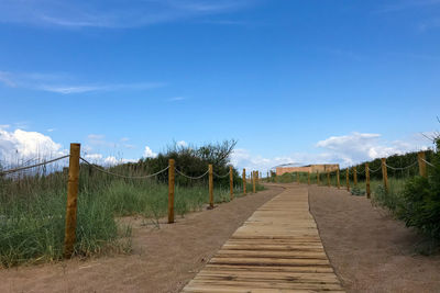 Footpath amidst field against sky