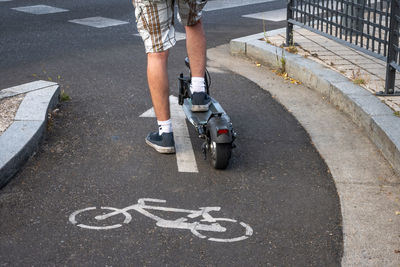 Detail of an electric scooter driven by a man while waiting his turn to cross a road. 