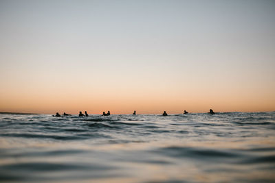 Silhouette people on beach against clear sky during sunset