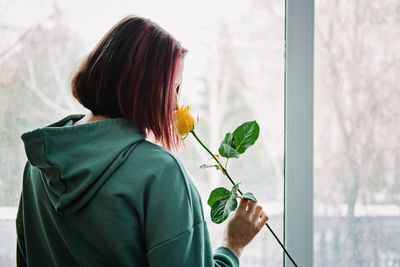 Rear view of young woman looking through window