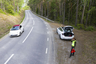 Man on side of road with broken down car