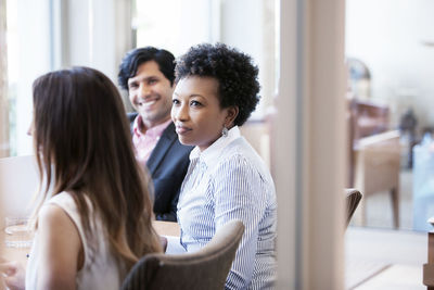 Mid adult woman looking at colleague during meeting in office