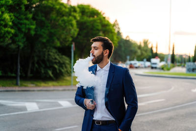 Young man looking away while standing on road