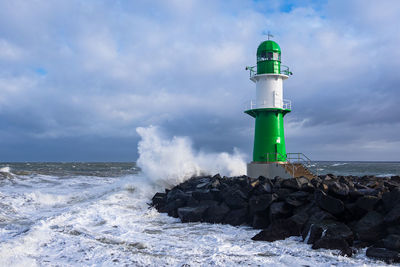 Lighthouse by sea against sky