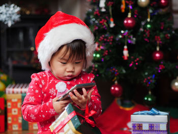 Close-up of baby girl using phone at home during christmas