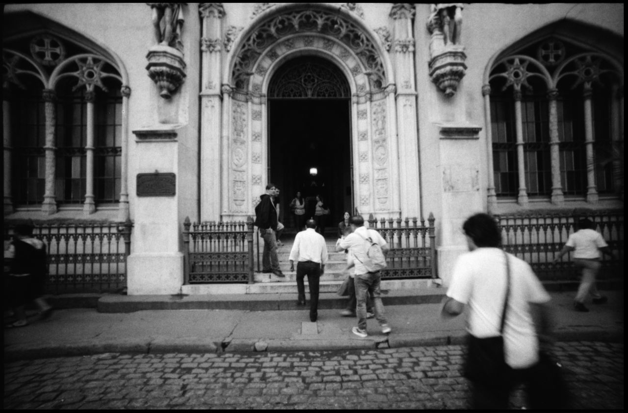 REAR VIEW OF PEOPLE WALKING ON STREET IN TEMPLE