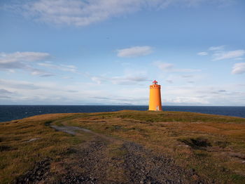 Lighthouse by sea against sky