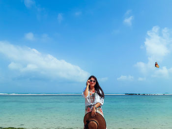 Woman standing at beach against sky