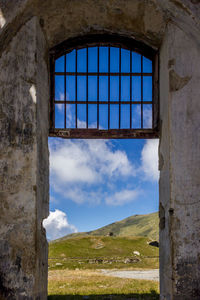 Abandoned building against blue sky seen through window