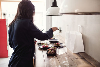 Woman preparing food in plate at table in workshop