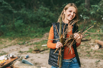 A tourist girl in nature collects firewood for a fire. a woman in close-up. 