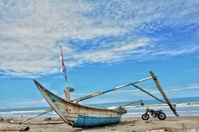 Abandoned boat on shore at beach against sky