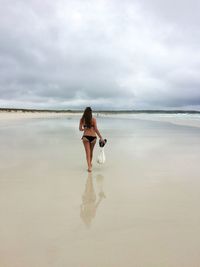 Rear view of young woman standing on beach