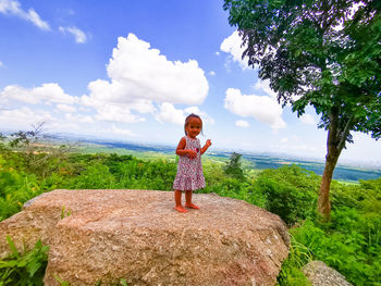 Baby girl against plants and trees against sky