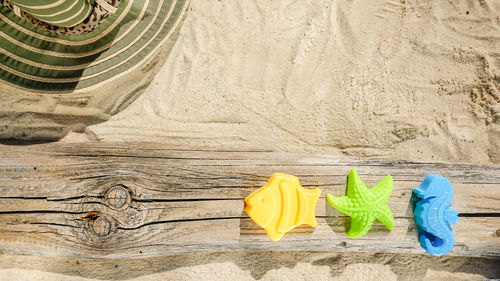 High angle view of multi colored toys for holiday at the sea on wood and sand. summer background. 