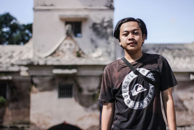 Portrait of young man standing against built structure