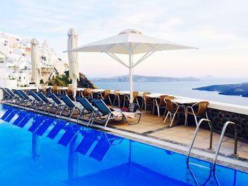 Lounge chairs and parasol by swimming pool at santorini