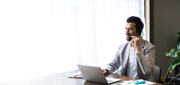 Young man using mobile phone while sitting on table