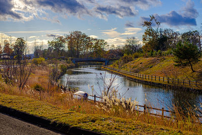 Arch bridge over river against sky during autumn