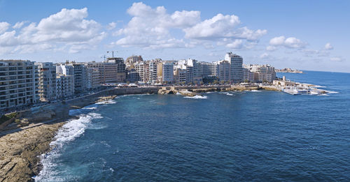 Sea by buildings against sky in city