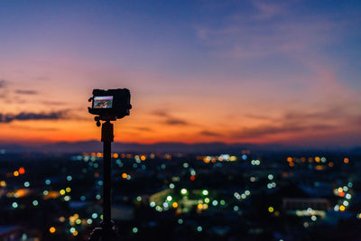 View of illuminated cityscape against sky during sunset