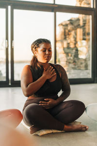 Plus size woman meditating while sitting cross-legged at retreat center