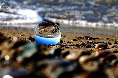 Close-up of water on glass at beach