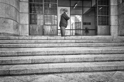 Side view of woman standing by staircase