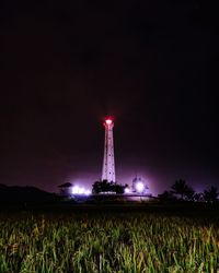 Illuminated tower on field against sky at night