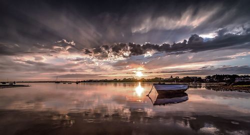 Boats moored on lake against sky during sunset