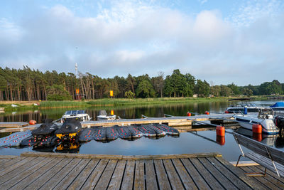 Boats moored by pier on lake against sky