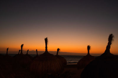 Silhouette people on beach against clear sky during sunset