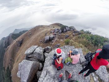 People on rock against mountain range