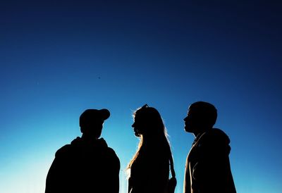Silhouette people against clear blue sky