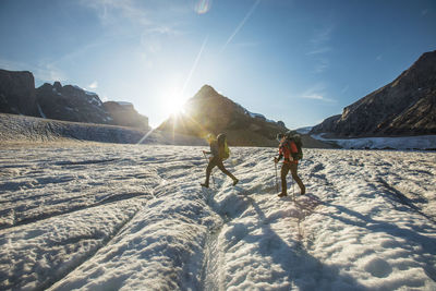 People on snow covered land against sky