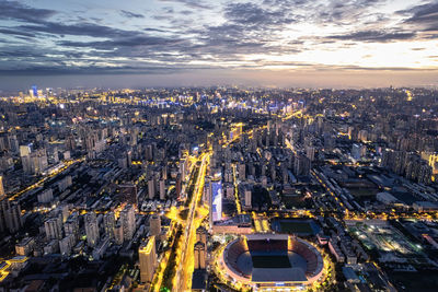 High angle view of illuminated street amidst buildings against sky during sunset