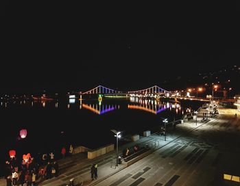 People on illuminated city against clear sky at night